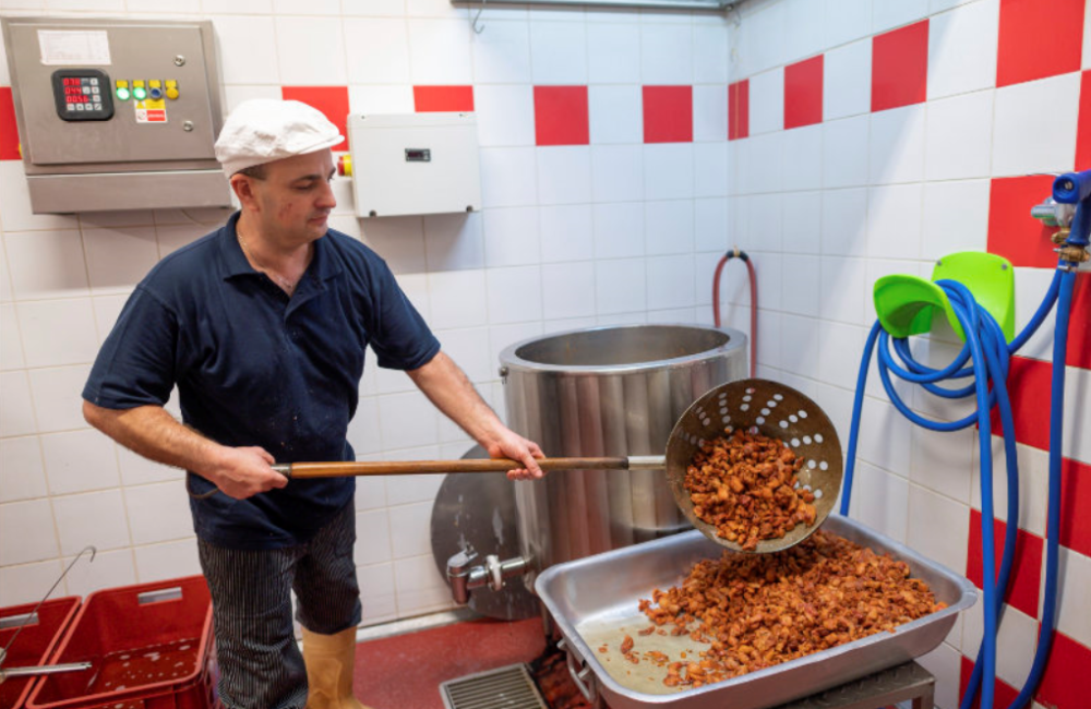 Zaměstnanec vyklápějící kusy masa do misi s velkou lyžicí